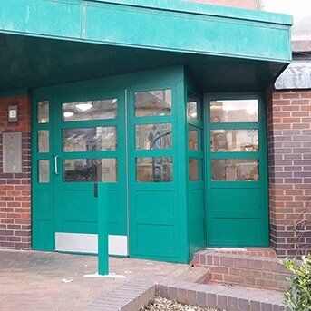 SECURED BY DESIGN COMMUNAL ENTRANCE DOOR SET FABRICATED IN STEEL TO LPS1175 SR2 STANDARD Green security door installation featuring multiple glass panels, designed for enhanced safety and aesthetic appeal, part of the Secure by Design accredited product range.