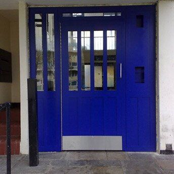 STEEL SECURED BY DESIGN PORTCULLIS DOOR SET INSTALLED IN LONDON BY PREMIER SECURITY CONSULTANTS Blue security door featuring glass panels, designed for communal access, reflecting Secure by Design standards and LPCB certification.