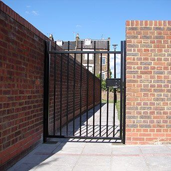 ROBUST STEEL GATE INSTALLED IN LONDON Black security gate in brick wall, showcasing Secure by Design accredited design for enhanced property safety.