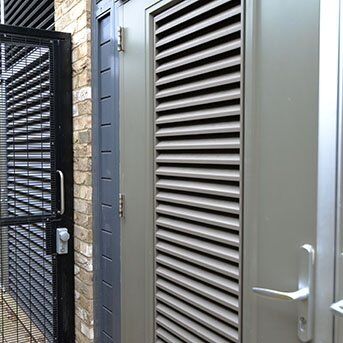 STEEL DOORS INCORPORATING LOUVRES. PAS24 AND SBD CERTIFIED. LPS1175 SR2 Secure by Design accredited louvre security door alongside a robust metal gate, showcasing strength and durability for high-security installations.