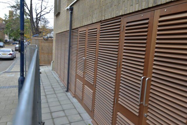 Louvre security doors installed along a side pathway, showcasing a Secure by Design accredited design for enhanced building safety and aesthetics.