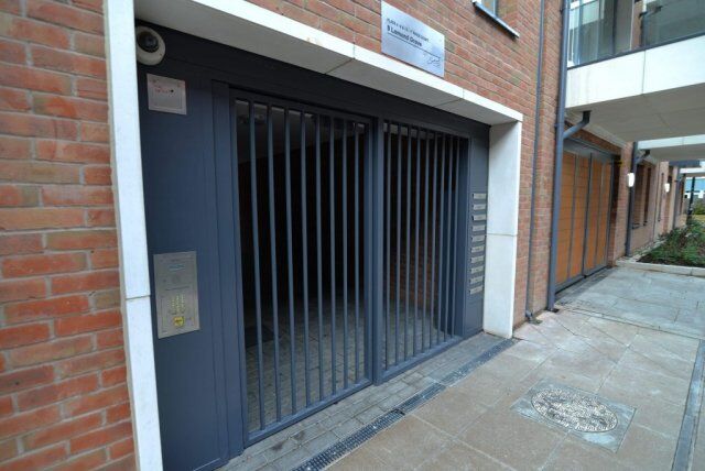 Secure by Design accredited steel security gate with vertical bars, intercom panel, and brick building backdrop, emphasizing safety and durability in residential access points.