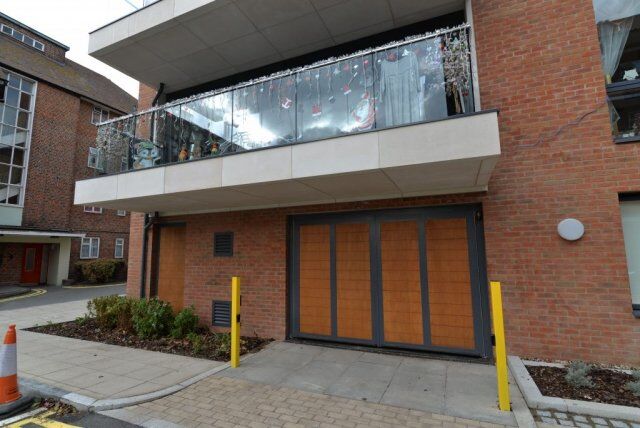 Secure by Design accredited industrial steel doors with wooden panels, located beneath a balcony in a residential setting, showcasing security features and aesthetic integration.