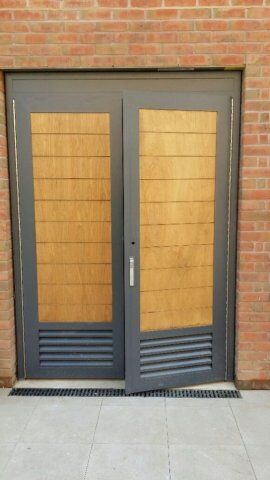Secure by Design accredited double doors featuring a modern wooden and grey metal design, suitable for enhancing security in residential and commercial properties.