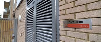 Plant room entrance with security door featuring louvre design, labeled sign indicating restricted access, enhancing safety in building design.