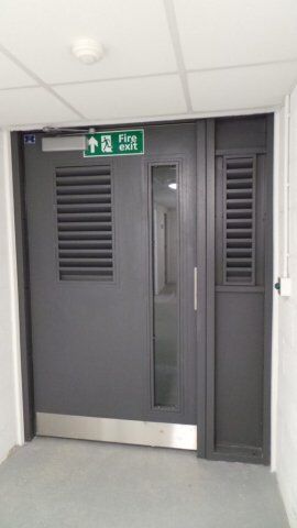 Secure by Design accredited fire exit door with ventilation louvres and glass panel, enhancing safety and accessibility in commercial settings.