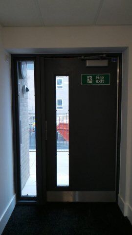 Secure by Design accredited fire exit door with glass panel, showcasing robust security features and compliance with safety standards.