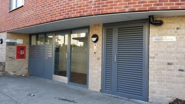 Modern entrance featuring Secure by Design accredited doors with louvre design, integrated intercom system, and adjacent mailbox, emphasizing security and aesthetic appeal for residential or commercial properties.