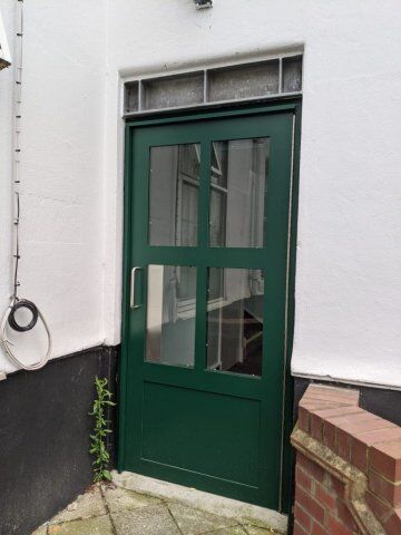Green security door with glass panels, designed for high durability and safety, part of Secure by Design accredited range.