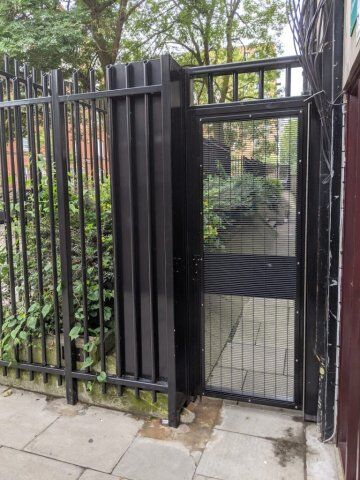 Secure by Design accredited security gate with mesh detailing, surrounded by greenery, enhancing safety and access control in urban settings.