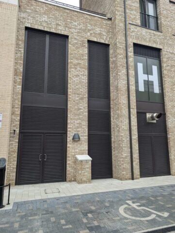 Secure by Design accredited communal steel doors with louvre features, set in a modern brick building, emphasizing safety and aesthetic compatibility.