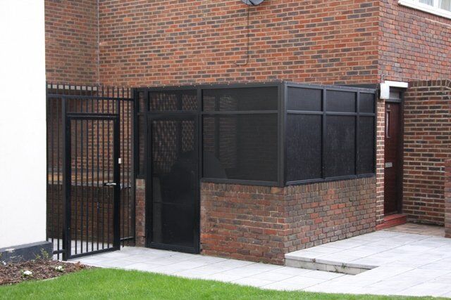 Secure by Design accredited black louvre bin store with gated access, showcasing durability and design compatibility with surrounding structures.