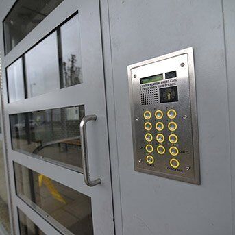 Secure by Design accredited intercom system with numeric keypad mounted on a glass security door, enhancing access control for residential and commercial properties.