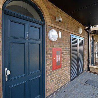 Secure by Design accredited blue security door with number 70, adjacent to a red mailbox and louvre doors, highlighting high-standard security solutions for residential properties.