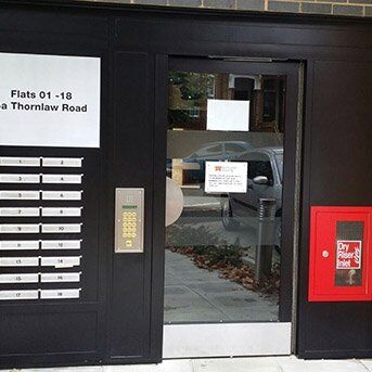 Communal entrance door with intercom system and mailboxes for flats, featuring a secure design for enhanced safety and access control.