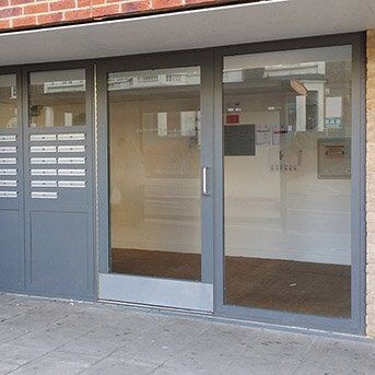Secure by Design accredited communal door with glass panels and grey frame, showcasing durability and modern design, suitable for residential and commercial security installations.