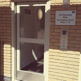 Entrance door of Harrington Court, featuring security intercom and signage for 26 Hornsey Rise, emphasizing secure access for residential flats.