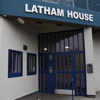 Entrance of Latham House featuring a secure blue door and multiple windows, emphasizing security design in commercial properties.