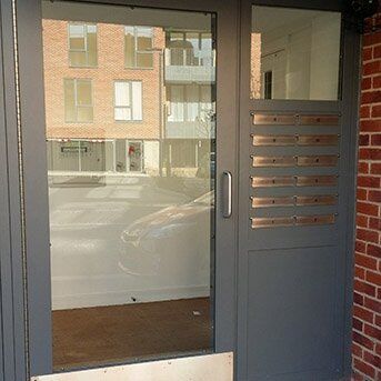 Secure by Design accredited communal door with glass panels and multiple mail slots, showcasing durability and modern design for enhanced building security.