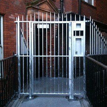 Secure by Design accredited security gate with vertical bars, featuring a pedestrian access door and intercom, enhancing safety for residential and commercial properties.