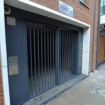 Secure by Design accredited steel security gates with vertical bars, leading to an entrance, showcased in a residential setting.