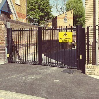 Automatic security gates with warning sign, showcasing a robust design for enhanced safety in residential or commercial properties, aligned with Secure by Design standards.