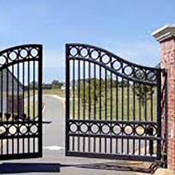 Black decorative security gates opening onto a driveway, showcasing a blend of aesthetic appeal and security features, relevant to Secure by Design accredited installations.