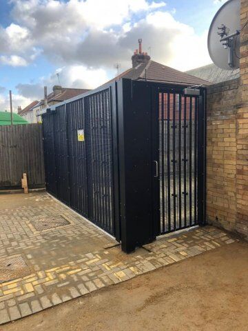 Secure by Design accredited black security gate with vertical bars, installed in a residential area, showcasing strength and durability for enhanced property safety.