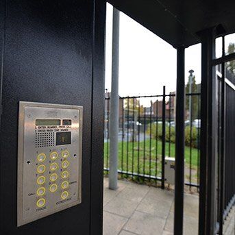 Security intercom panel with keypad at a gated entrance, showcasing access control for Secure by Design accredited installations.
