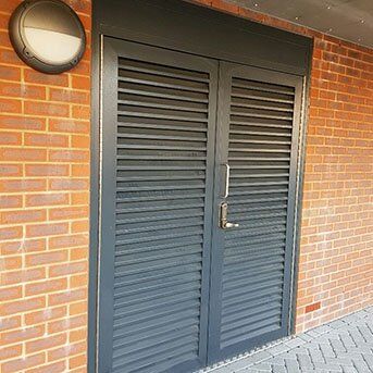Secure by Design accredited louvre security door with robust design, installed in a brick wall setting, showcasing strength and durability for enhanced property safety.
