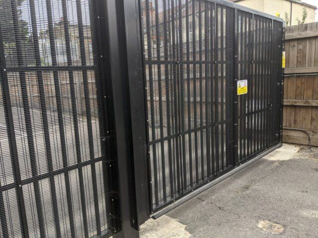 Automated security gate with mesh design, featuring a warning sign, enhancing safety and access control in residential or commercial properties.